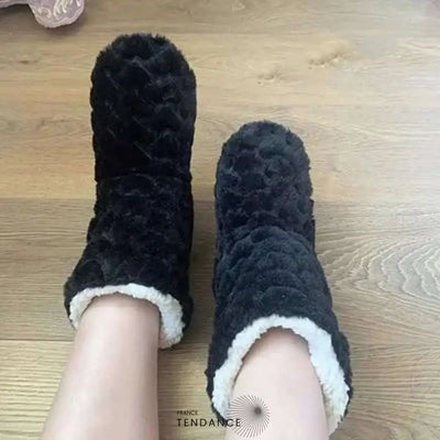 Chaussons bottines noirs portés sur un parquet