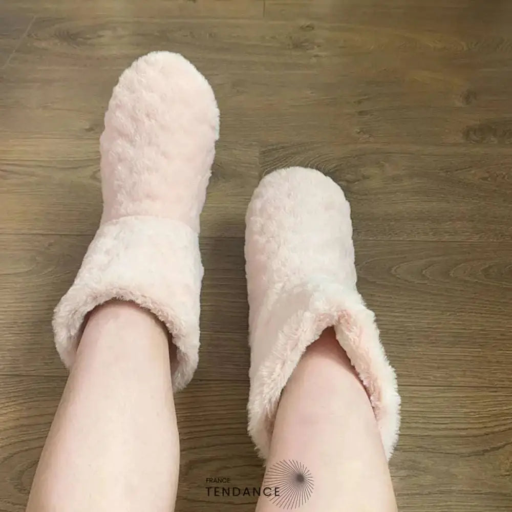 Pantoufles montantes rose pâle fourrées, portées sur un parquet