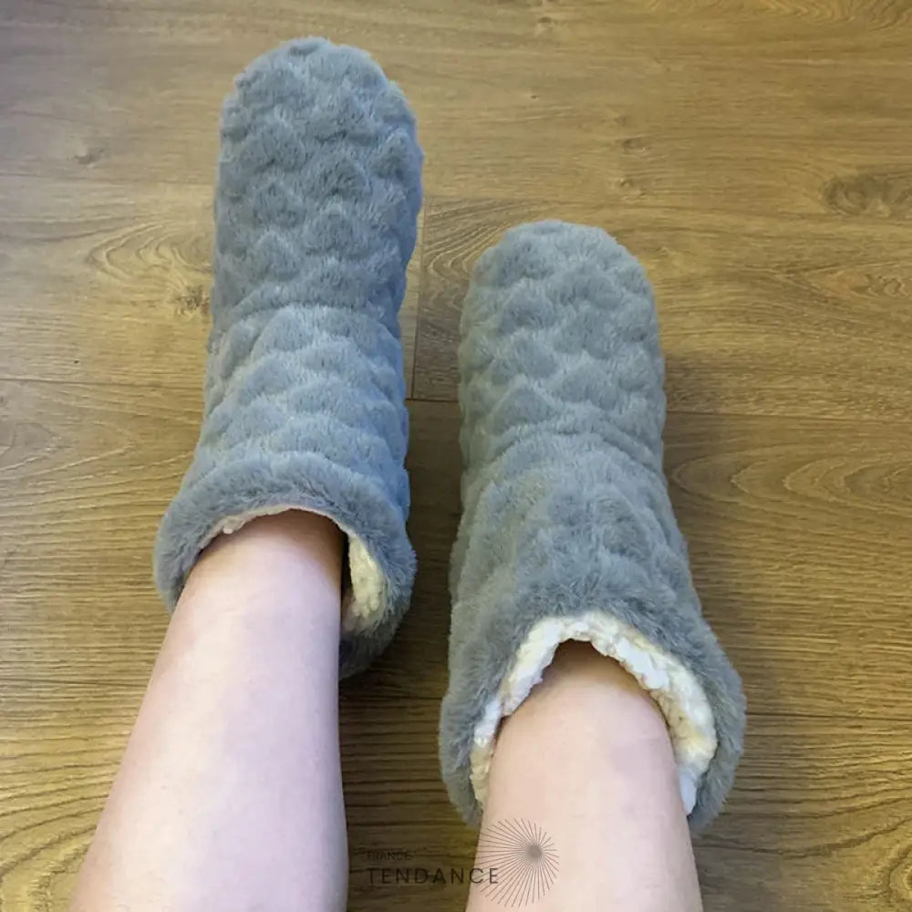 Pantoufles montantes grises fourrées, portées sur un parquet